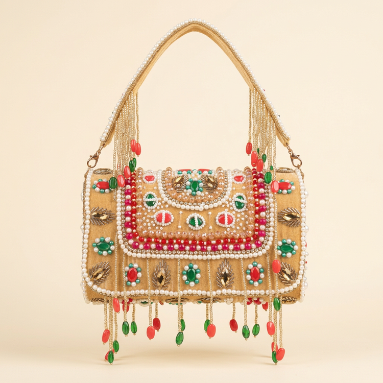 Jewelled gold tassel bag with red and green stones on a cream studio background