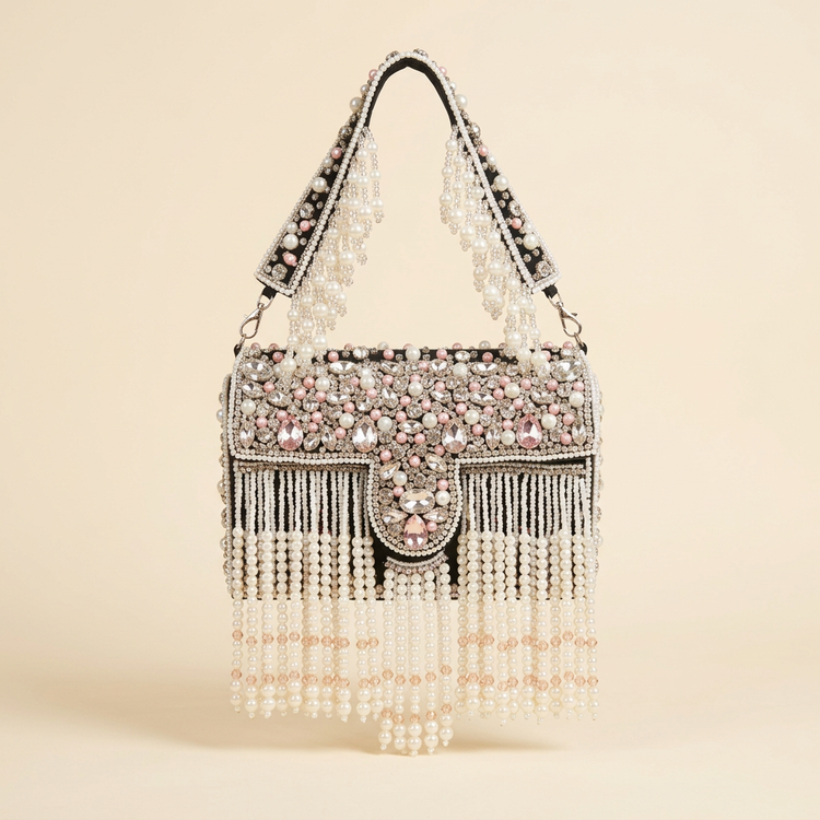 Black box bag with blush crystals and pearl fringe on a cream studio background