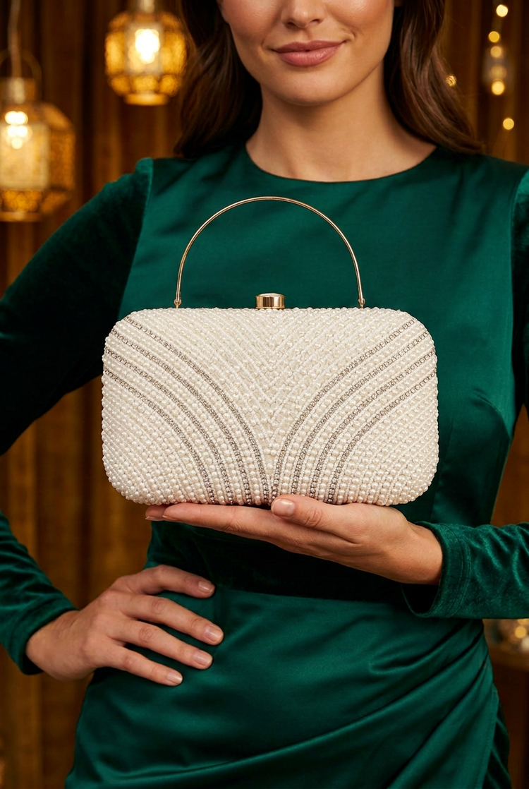 Pearl Arches ivory clutch supported on the model’s palm with emerald festive occasionwear