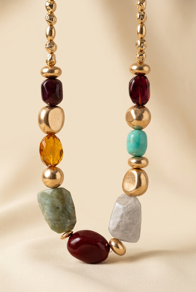 Multicolour faceted bead and gold necklace on a cream studio background