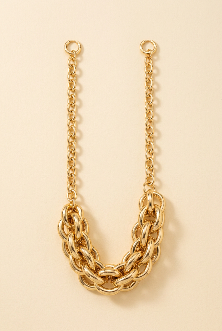Chunky interlocking gold chain necklace on a cream studio background