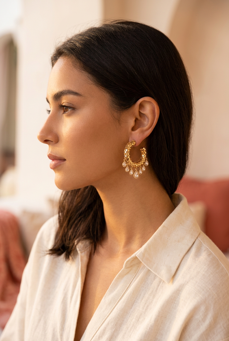 Woman in a cream linen shirt wearing small gold mesh crystal fringe hoops