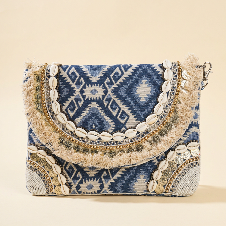 Blue Aztec shell and coin boho clutch on a cream studio background