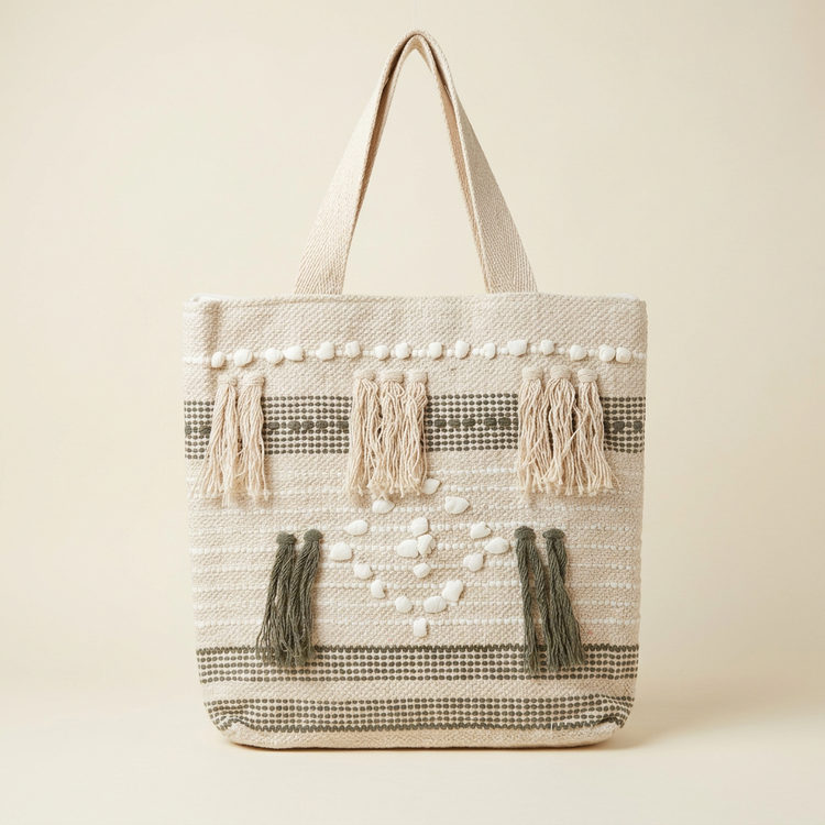 Cream and grey woven tote with white shell accents and tassels, studio view
