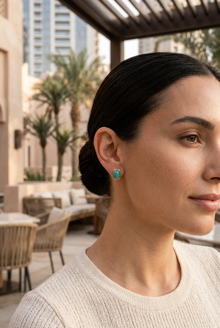 Aqua oval gold studs worn at a Dubai cafe terrace