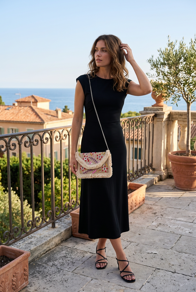 Small ivory floral clutch with long silver chain and black dress, AI-generated lifestyle image
