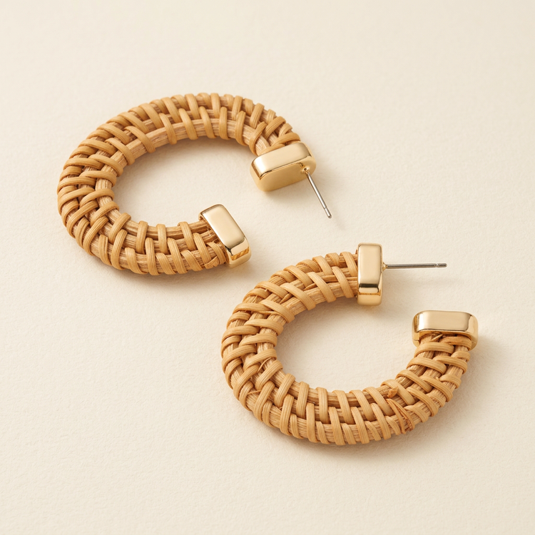 Natural woven hoop earrings with gold-tone end caps, studio view