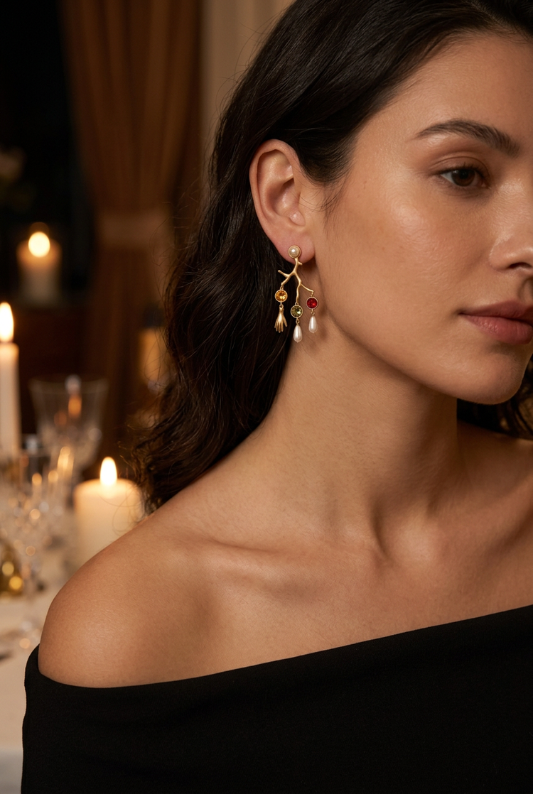 Gold coral branch charm earrings worn at a candlelit dinner