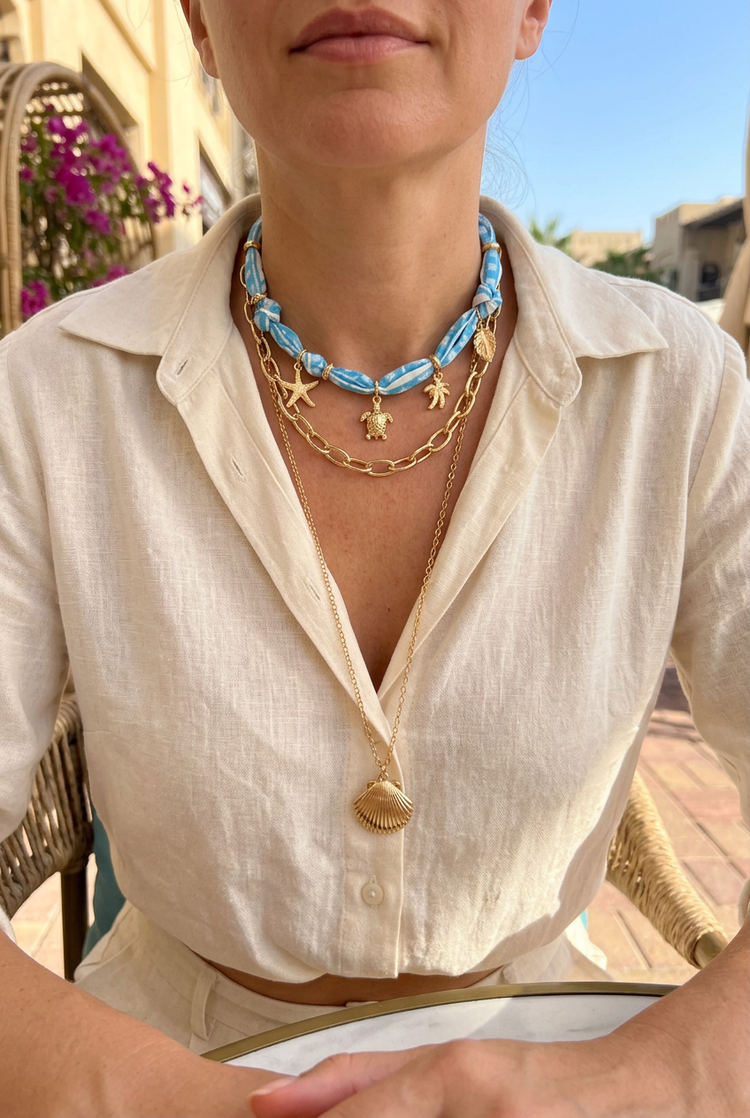 Blue scarf and gold seashell necklace worn with cream linen