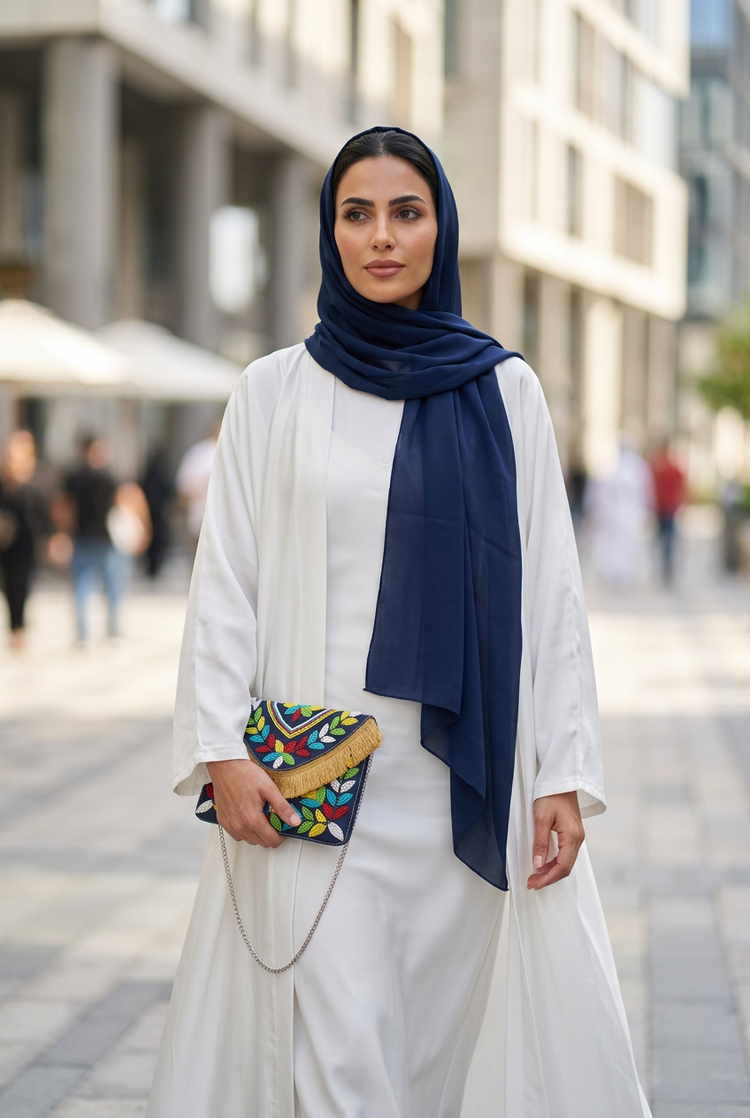 Navy multicolour leaf beaded fringe clutch held with a white abaya and navy shayla in Dubai Design District
