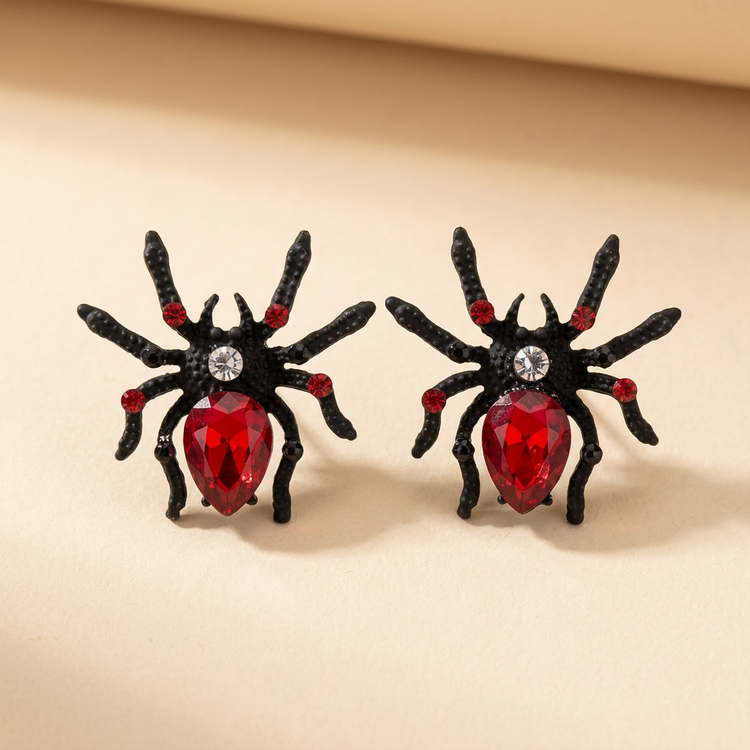 Black rubber spider earrings with red stones on cream studio background