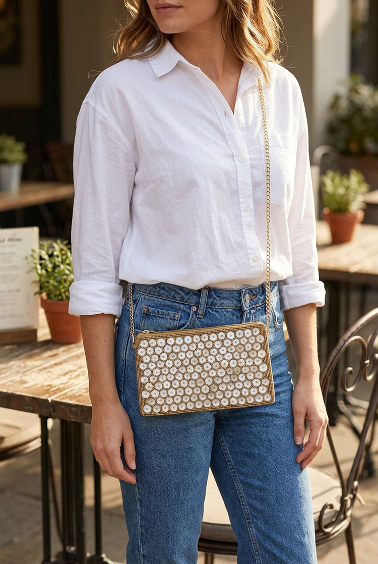 Shell Glow small shell-disc sling bag worn with a white shirt and blue jeans at a cafe