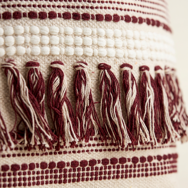 Close-up of burgundy woven stripes, white bobble band and two-tone tassels
