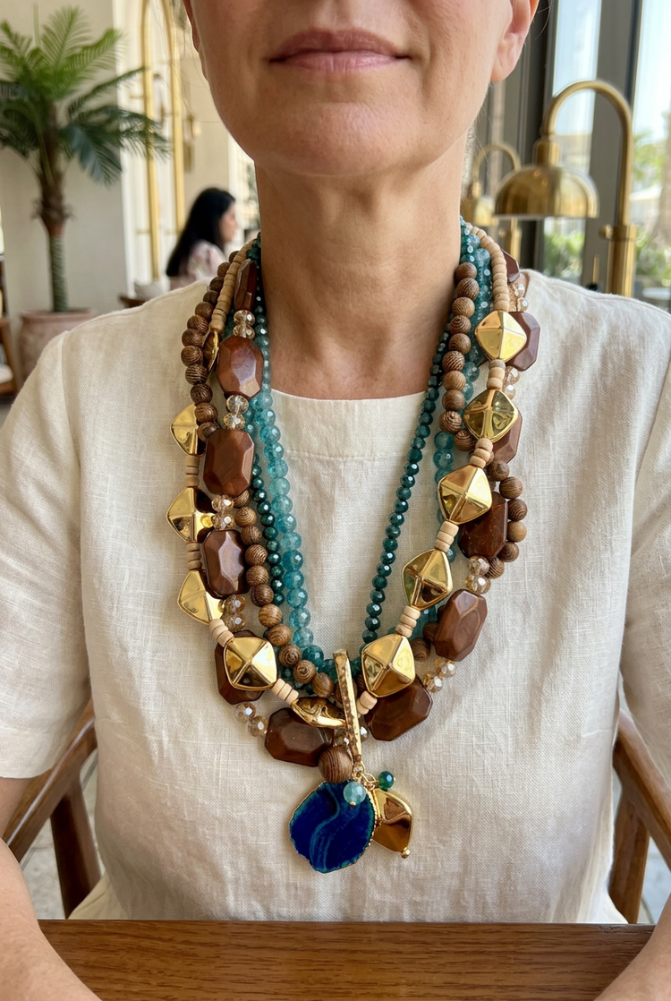 Teal and brown multistrand blue pendant necklace worn with ivory linen