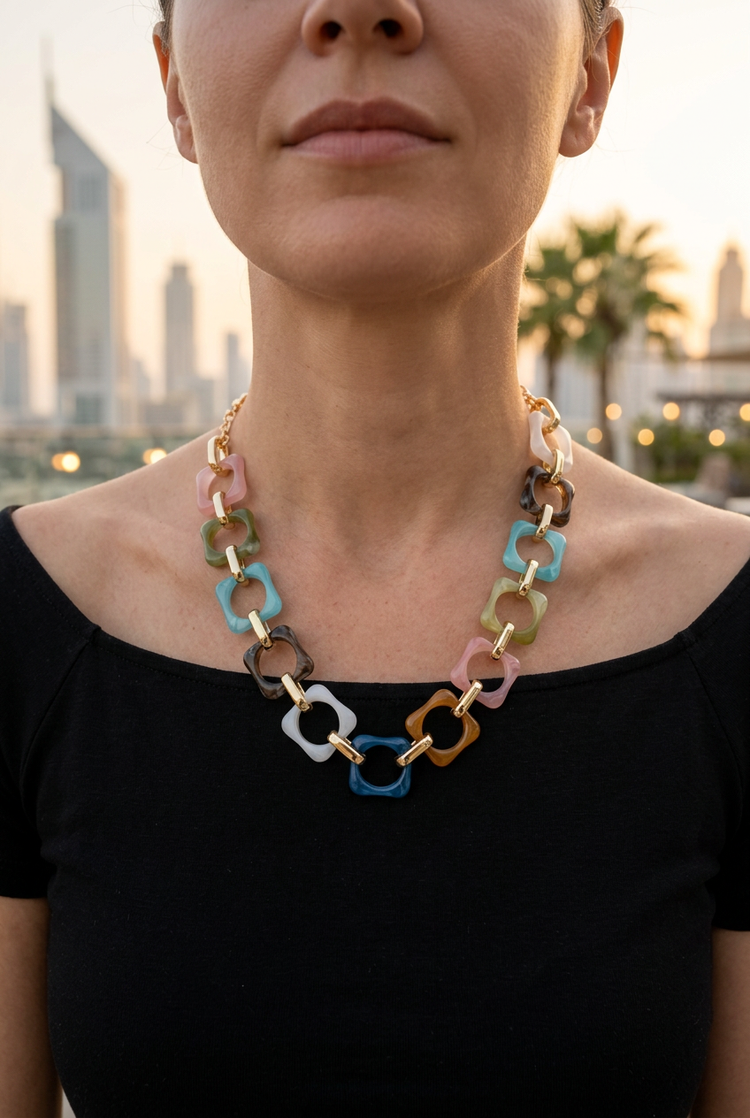 Small multicolour square-link necklace worn with a black neckline