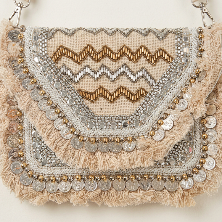 Close-up of metallic zigzag beadwork and ivory fringe on clutch