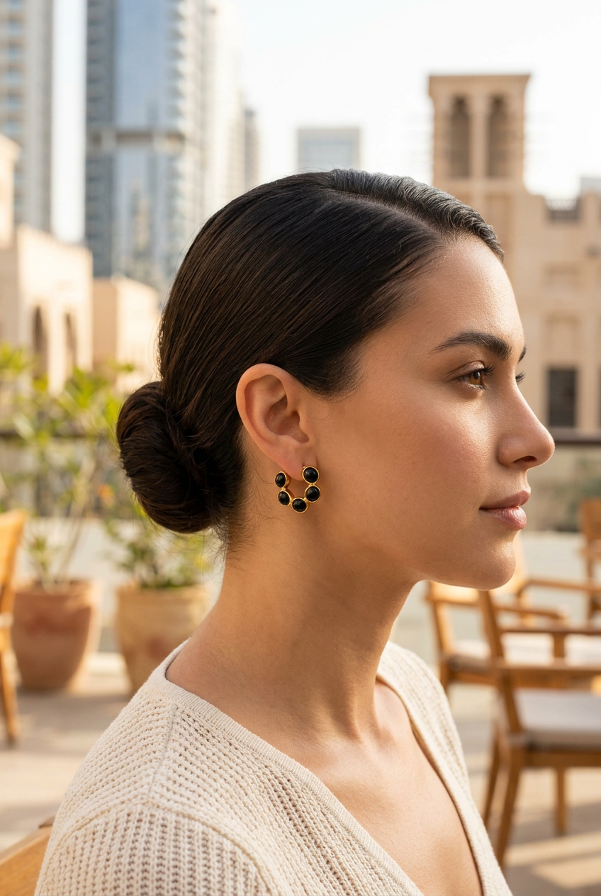 Small black pebble gold hoops worn at a Dubai cafe